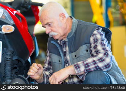 senior motorcycle mechanic working at his workshop