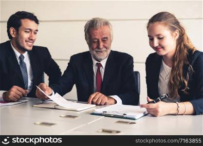 Senior old executive manager working with young businesspeople in office meeting room. Old man is the company leader sitting with secretary and translator. International corporate business concept.