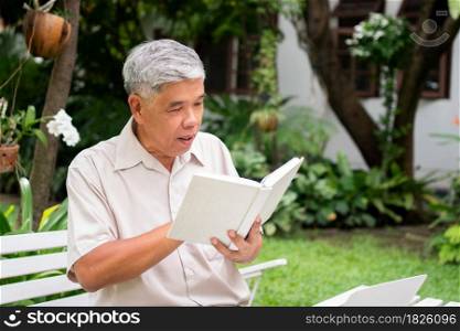 senior old man reading a book in the park. Concept of retirement lifestyle and hobby.
