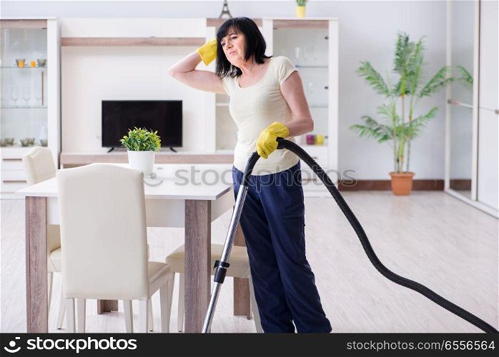 Senior old woman tired after vacuum cleaning house