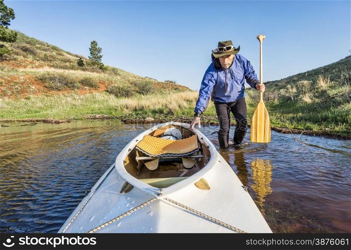 senior paddler and decked expedition canoe on the shore of Horsetooth Reservoir, Fort Collins, Colorado, springtime scenery