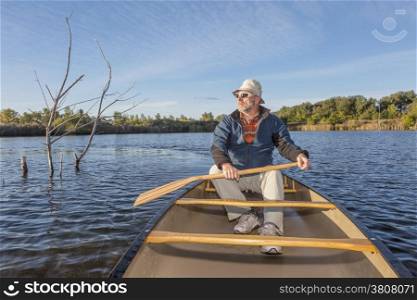 senior paddler enjoying morning sun on lake in a canoe, Riverbend Ponds Natural Area, Fort Collins, Colorado