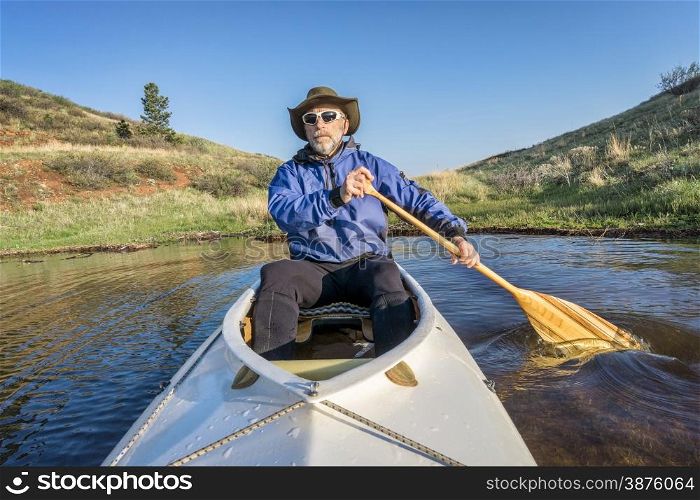 senior paddler in a decked expedition canoe on Horsetooth Reservoir, Fort Collins, Colorado, springtime scenery