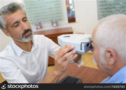 senior patient while sitting with optician in clinic