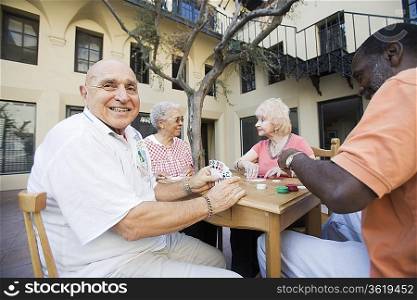 Senior people playing cards, smiling