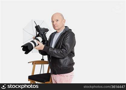 Senior photographer holding camera in studio