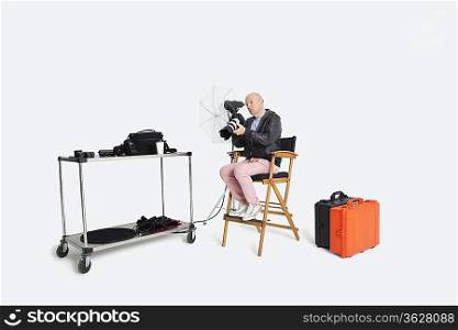 Senior photographer looking at camera while sitting on director&acute;s chair in studio