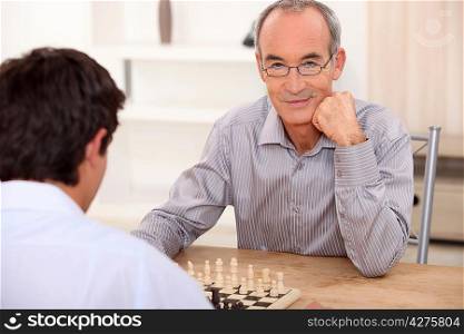 senior playing chess with grandson