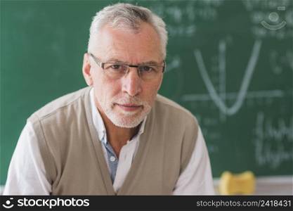 senior professor looking camera against chalkboard with math example
