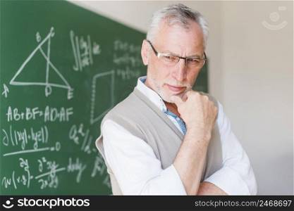 senior professor standing near chalkboard lecture room