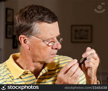 Senior repairing an old pocket watch with screwdriver and wearing very strong lens glasses to magnify the mechanism