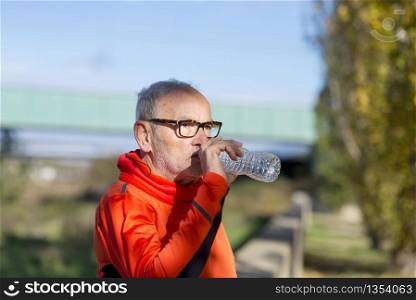 Senior runner drinking water after jogging