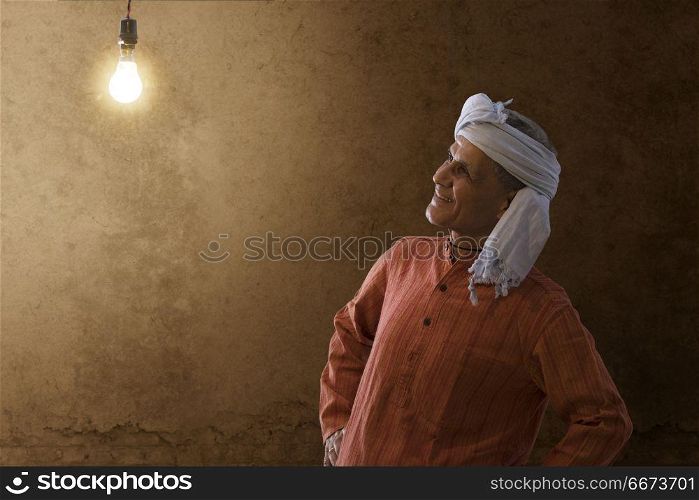 Senior rural man looking at light bulb in his house