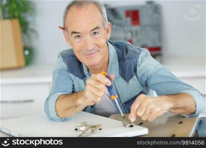 senior satisfied carpenter tightening screws