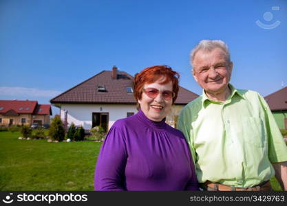 Senior smiling couple in front of their new house