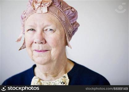 Senior smiling woman in the studio wearing a vintage hat and lace.