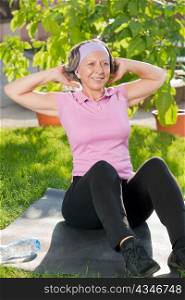 Senior sportive woman exercising on mat doing sit-ups sunny outdoor