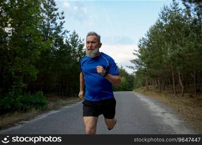 Senior sportsman running among countryside road. Physical endurance training and cardio exercise for pensioner. Senior sportsman running among road