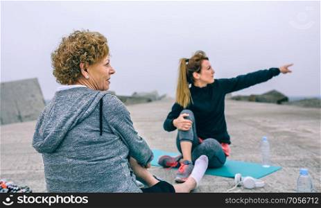 Senior sportswoman looking at what the young woman is pointing. Senior sportswoman with woman pointing