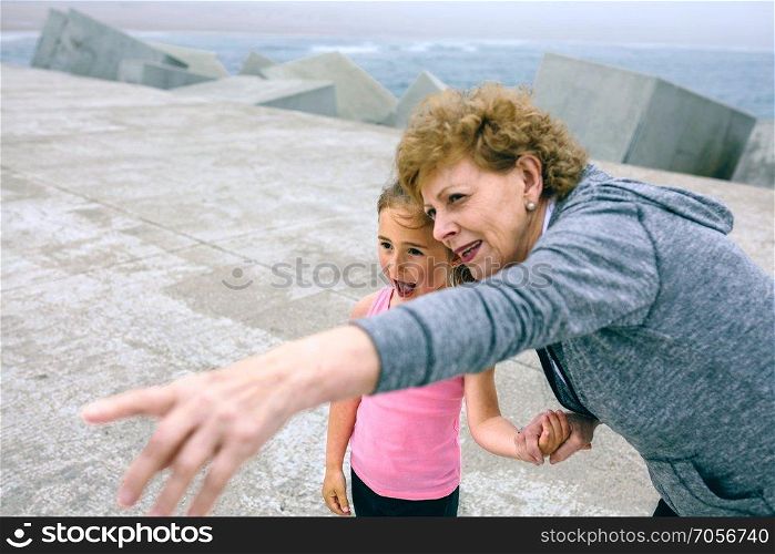 Senior sportswoman pointing while little girl is surprised. Senior sportswoman pointing with little girl