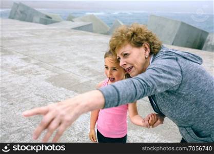 Senior sportswoman pointing while little girl is surprised. Senior sportswoman pointing with little girl