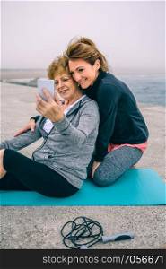 Senior sportswoman taking selfie with coach by sea pier. Senior sportswoman taking selfie with coach