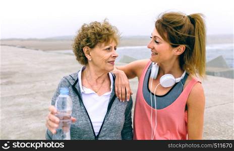 Senior sportswoman talking with female friend by sea pier. Senior sportswoman talking with female friend