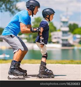 Senior teacher of roller skating with little boy practicing on class in the park