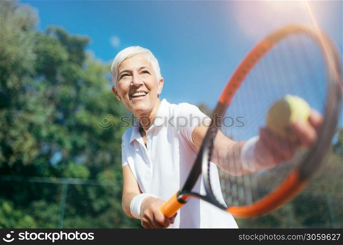 Senior Tennis ? Pretty Mature Woman Serving Ball in Tennis