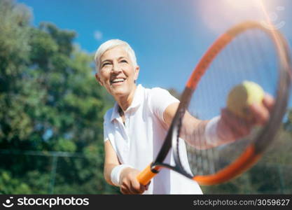 Senior Tennis ? Pretty Mature Woman Serving Ball in Tennis