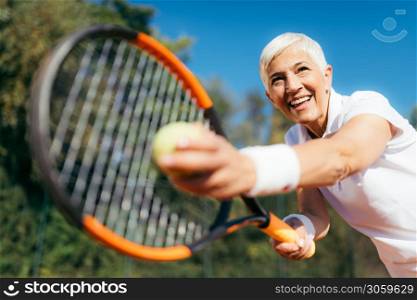 Senior Tennis ? Pretty Mature Woman Serving Ball in Tennis