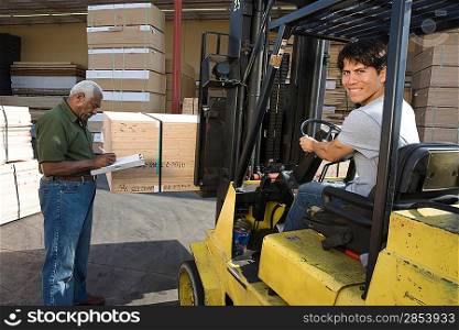 Senior warehouseman and mid-adult forklift truck driver