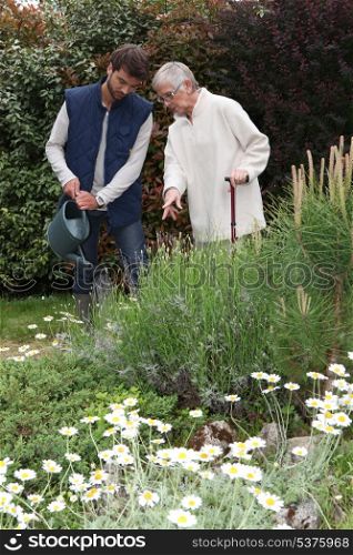 Senior with gardener watering plants