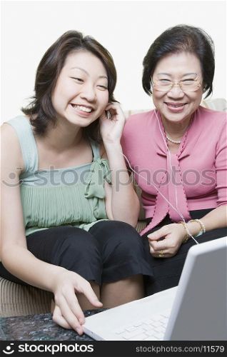 Senior woman and her granddaughter using a laptop and listening to music