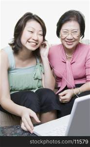 Senior woman and her granddaughter using a laptop and listening to music