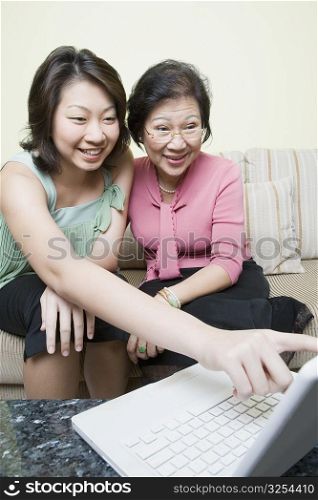 Senior woman and her granddaughter using a laptop and smiling