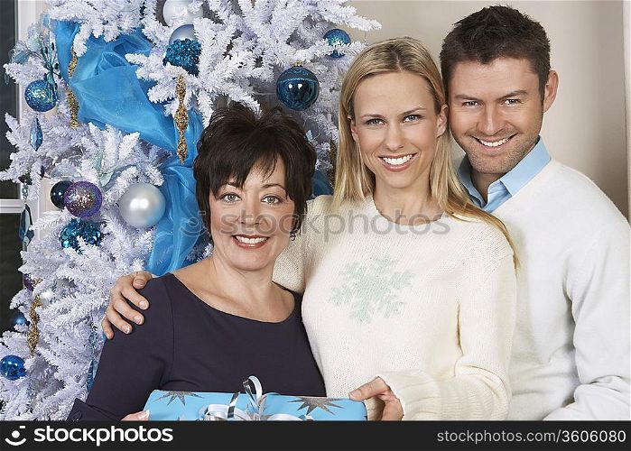 Senior woman and mid adult couple in front of Christmas tree, portrait