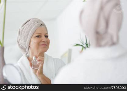 senior woman applying perfume