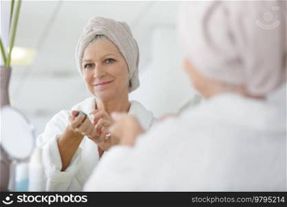 senior woman at dressing table mirror applying perfume