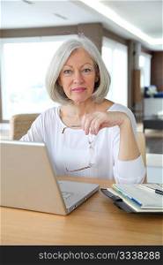 Senior woman at home in front of laptop computer
