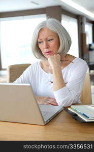 Senior woman at home in front of laptop computer