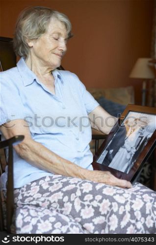Senior Woman At Home Looking At Old Wedding Photo