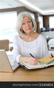 Senior woman at home writing on agenda