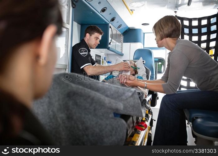 Senior woman being given oxygen in an ambulance, caregiver at side