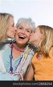 Senior woman being kissed by daughter and granddaughter