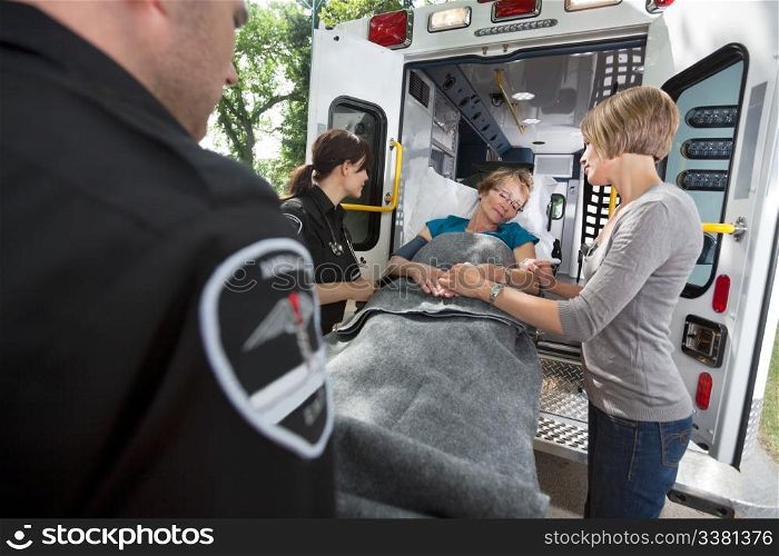 Senior woman being loaded onto ambulance with caregiver at side