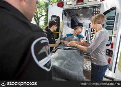 Senior woman being loaded onto ambulance with caregiver at side