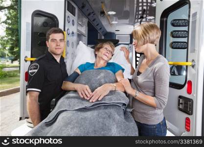 Senior woman being taken on ambulance, daughter at side