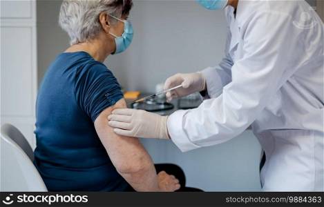 Senior woman being vaccinated against coronavirus by a female doctor