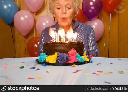 Senior woman blowing out candles on cake